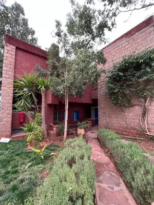 a red brick building with a tree in front of it at Atlas AGUELMAM in Bine el Ouidane