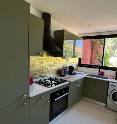 a kitchen with green cabinets and a stove top oven at Atlas AGUELMAM in Bine el Ouidane