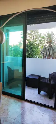 a screened in porch with glass doors and a couch at APPARTEMENTS NIA CONFORT, Plein centre ville, avec TERRASSE in Fès