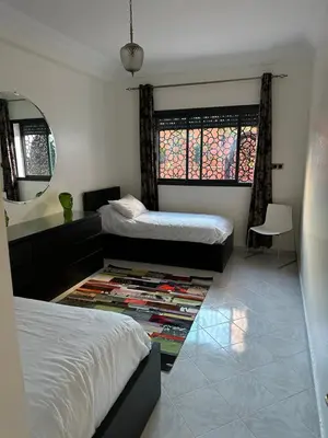 a bedroom with two beds and a rug at APPARTEMENTS NIA CONFORT, Plein centre ville, avec TERRASSE in Fès