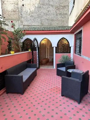 a patio with chairs and tables on a pink building at APPARTEMENTS NIA CONFORT, Plein centre ville, avec TERRASSE in Fès