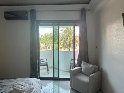 a bedroom with a bed and a chair and a balcony at APPARTEMENTS NIA CONFORT, Plein centre ville, avec TERRASSE in Fès