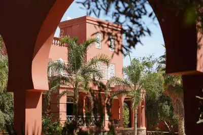 a pink building with palm trees in front of it at La Palmeraie De Moulay Yacoub in Moulay Yacoub