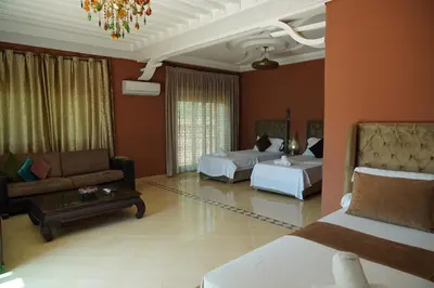 a living room with two beds and a couch and a room with two beds at La Palmeraie De Moulay Yacoub in Moulay Yacoub