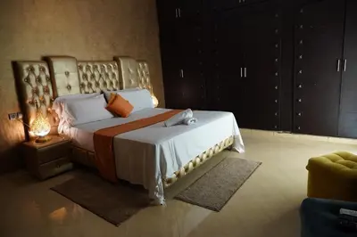 a bedroom with a large bed with a wooden headboard at La Palmeraie De Moulay Yacoub in Moulay Yacoub