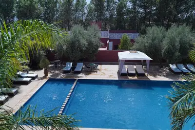 a swimming pool with lounge chairs and a table in a yard at La Palmeraie De Moulay Yacoub in Moulay Yacoub
