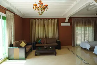 a living room with a couch and a bed and a chandelier at La Palmeraie De Moulay Yacoub in Moulay Yacoub