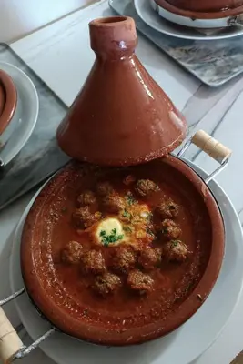 a dish of food with meatballs and sauce on a stove at Hotel Riad Taounate in Taounate