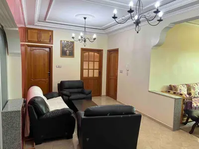 a living room with black leather furniture and a chandelier at Appartement chaleureux Azrou in Azrou
