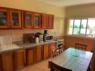 a kitchen with wooden cabinets and a table with a microwave at Appartement chaleureux Azrou in Azrou