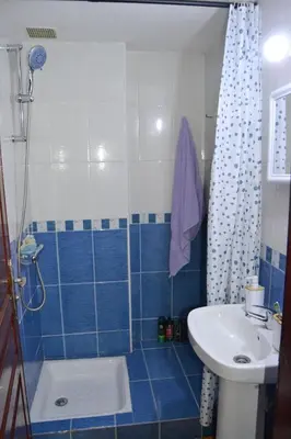 a blue tiled bathroom with a sink and a shower at holiday apartment rental in Meknès