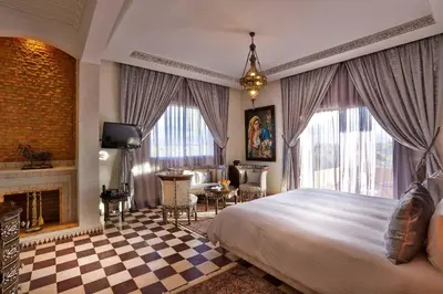 a bedroom with a large bed and a fireplace at Palais Amador in Marrakech