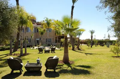 a park with chairs and palm trees and a building at Palais Amador in Marrakech