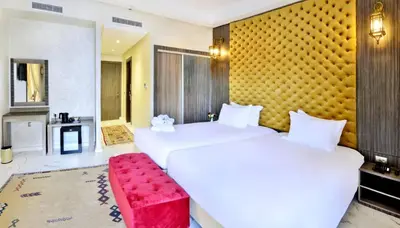 two beds in a hotel room with a red bench at Fes Heritage Boutique luxury Hotel in Fès