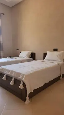 a bedroom with two beds with white sheets at Villa privative tortues2 piscine chauffée 35min Marrakech in Marrakech