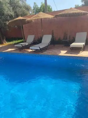 two white chairs and a blue swimming pool at Villa privative tortues2 piscine chauffée 35min Marrakech in Marrakech