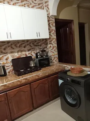 a kitchen with a washing machine and a microwave at Résidence Jannat in Ouarzazate