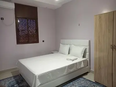 a bedroom with a bed with white sheets and a window at Résidence Jannat in Ouarzazate