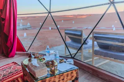 a table and chairs with a view of the beach at Luxury Camp Camelhouse in Merzouga