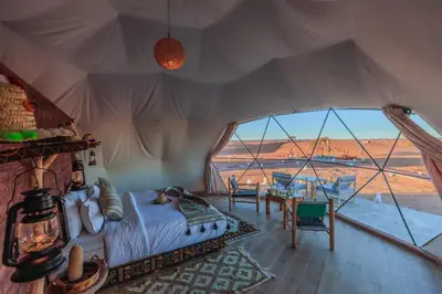 a bedroom with a bed and a large window at Luxury Camp Camelhouse in Merzouga