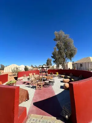 a patio with tables and chairs and a playground at Luxury Camp Camelhouse in Merzouga