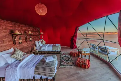 a bedroom with two beds in a red tent at Luxury Camp Camelhouse in Merzouga