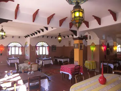 a restaurant with tables and chairs in a room at Kasba Oum Hani d'Ouzoud in Ouzoud
