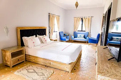 a bedroom with a large bed and blue chairs at Dar Lily, villa familiale avec piscine et services in Skoura