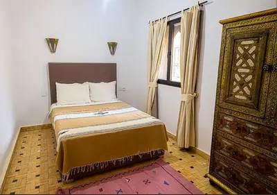 a bedroom with a bed and a window and a dresser at Dar Lily, villa familiale avec piscine et services in Skoura