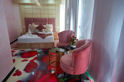 a bedroom with two pink chairs and a bed at FEKRI HOTEL in Meknès