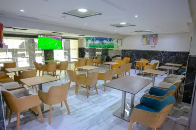 a restaurant with tables and chairs and a tv at FEKRI HOTEL in Meknès