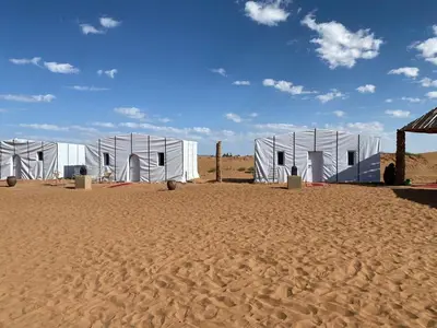 a row of white tents in the desert at Desert Erg Chegaga Camp in El Gouera
