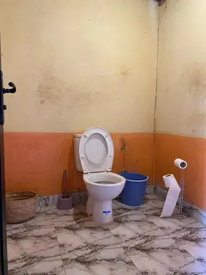 a bathroom with a toilet and a blue bucket at Desert Erg Chegaga Camp in El Gouera