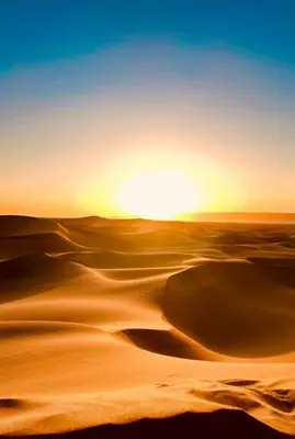 a desert with the sun rising over the horizon at Desert Erg Chegaga Camp in El Gouera