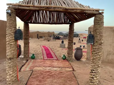 a pavilion in the desert with a red carpet and a table at Desert Erg Chegaga Camp in El Gouera