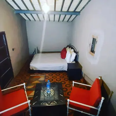a room with a bed and two chairs and a table at Desert Erg Chegaga Camp in El Gouera
