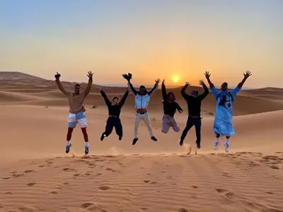 a group of people jumping in the desert at Luxury Desert Central Camp in Merzouga