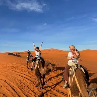three people riding on camels in the desert at Luxury Desert Central Camp in Merzouga