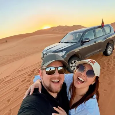 a man and a woman in the desert with a car at Luxury Desert Central Camp in Merzouga