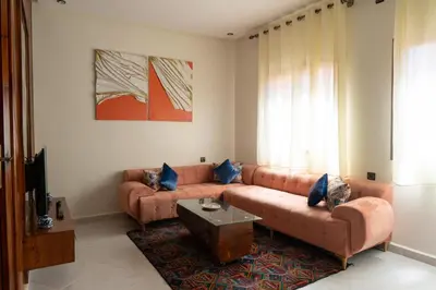 a living room with a brown couch and a table at Imlil apartment climatisé in Azrou