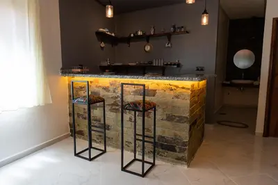 a kitchen with a counter with three bar stools at Imlil apartment climatisé in Azrou