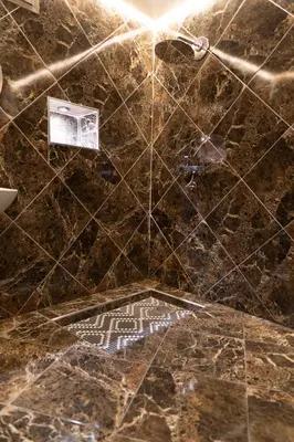 a bathroom with a shower with a marble tile floor at Imlil apartment climatisé in Azrou