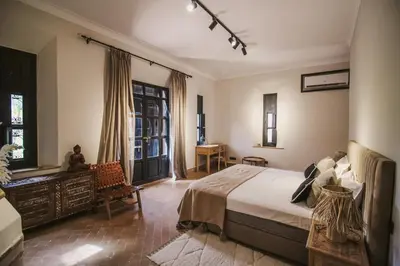 a bedroom with a bed and a desk and windows at Villa Beij in Marrakech