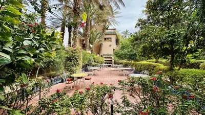 a garden with tables and chairs and trees at Chez Ali Zagora Authentic Hotel Restaurant and Desert Excursions in Zagora