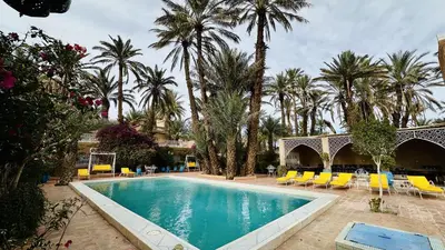 a swimming pool with yellow chairs and palm trees at Chez Ali Zagora Authentic Hotel Restaurant and Desert Excursions in Zagora