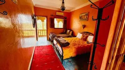 a bedroom with a bed and a red wall at Chez Ali Zagora Authentic Hotel Restaurant and Desert Excursions in Zagora