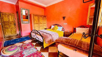 a bedroom with two beds and orange walls at Chez Ali Zagora Authentic Hotel Restaurant and Desert Excursions in Zagora