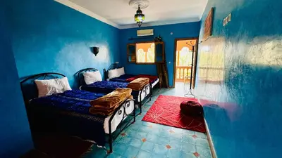 two beds in a room with blue walls at Chez Ali Zagora Authentic Hotel Restaurant and Desert Excursions in Zagora