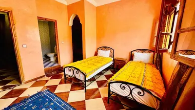 two beds with yellow covers in a room with a tiled floor at Chez Ali Zagora Authentic Hotel Restaurant and Desert Excursions in Zagora