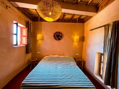 a bedroom with a bed with a blue and white stripes at Auberge Ayouze in Aït Ben Haddou